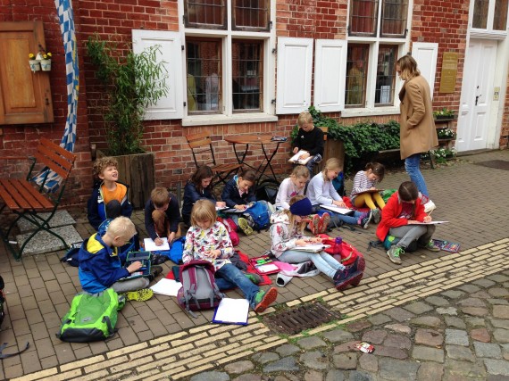 Schülerinnen und Schüler sitzen auf der Straße im holländischen Viertel beim Malen der Häuserbilder